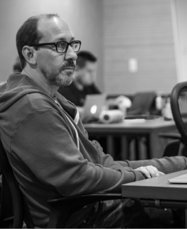 Photo of Darin Wilson sitting at a table listening to a presentation