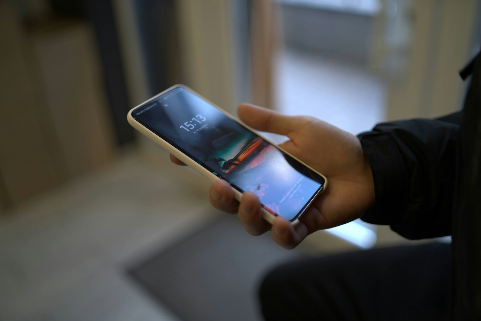 A hand holding a Samsung Android phone showing its lock screen